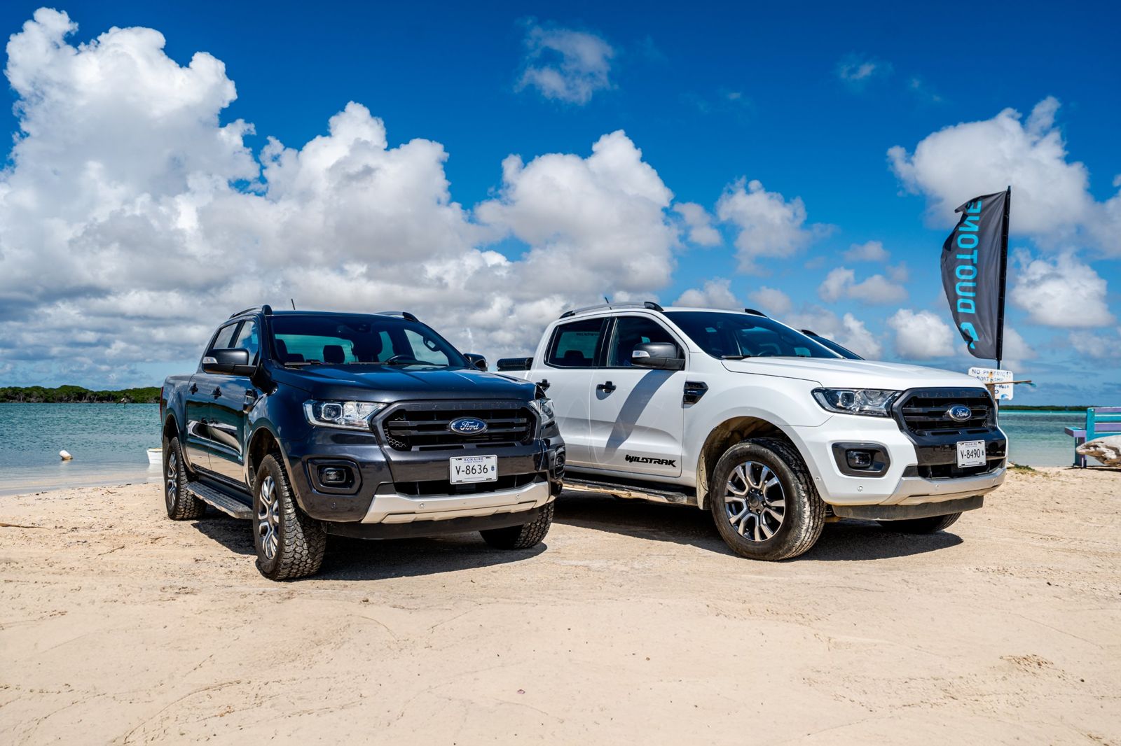 Twee Ford Rangers op het strand bij Lac Bay